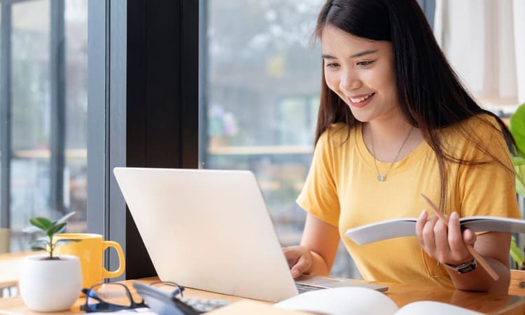 一名學生手上拿著筆記本正在操作筆電