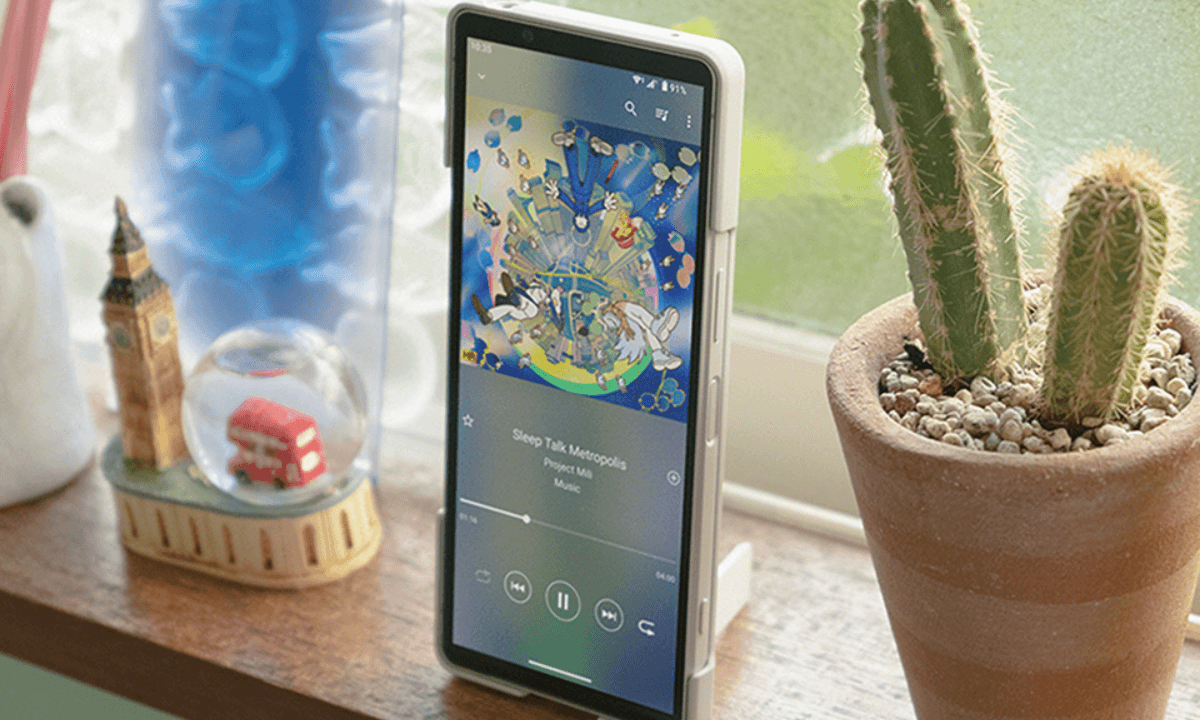 Sony Xperia 手機直立放置於窗邊,螢幕正播放音樂,旁邊擺有仙人掌盆栽與倫敦主題擺飾