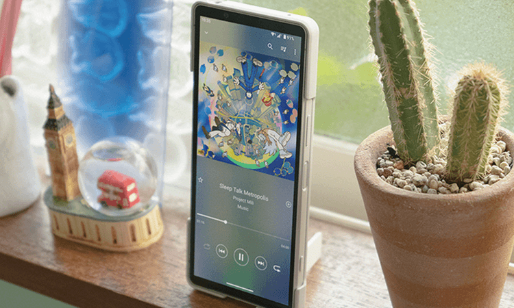 Sony Xperia 手機直立放置於窗邊,螢幕正播放音樂,旁邊擺有仙人掌盆栽與倫敦主題擺飾