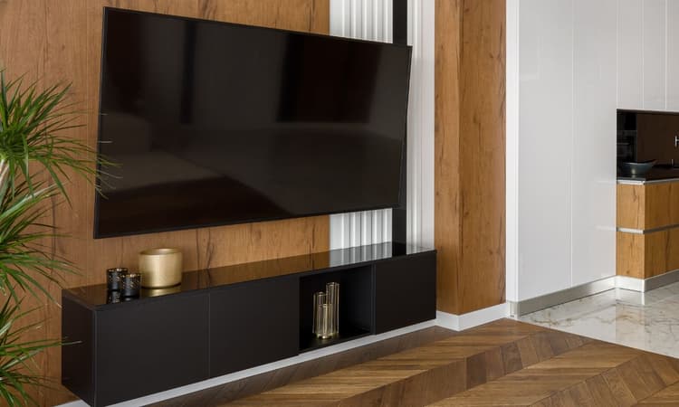 客廳擺放一台壁掛式65吋電視與簡約黑色電視櫃