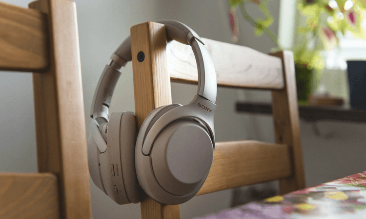 SONY 銀灰色耳罩式耳機掛在木質椅背上